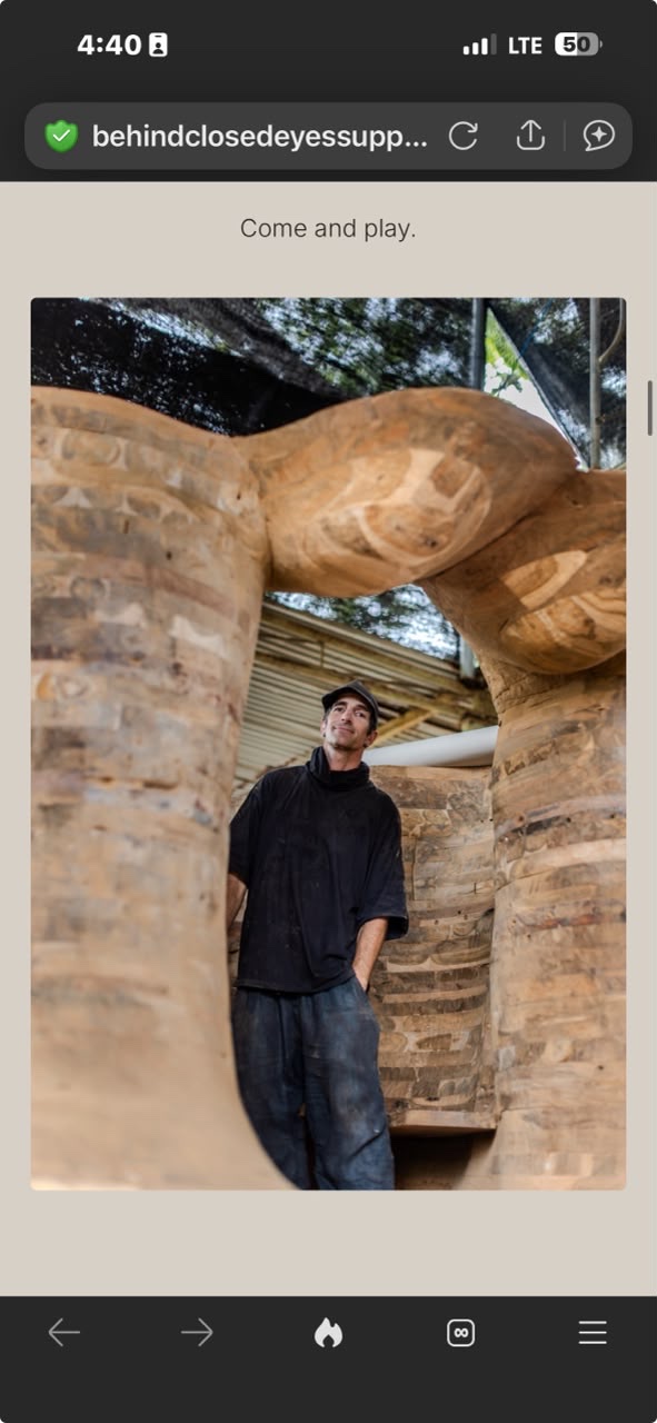 Spencer Hansen standing under the half-finished Behind Closed Eyes sculpture